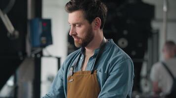 Caucasian man working in factory roasting coffee beans roaster machine industrial production aroma caffeine check quality male guy smiling looking camera technologist barista in apron roast technology video