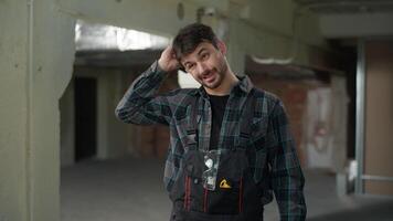 Man builder engineer on construction site working rubbing head thoughtful male Caucasian guy architect handyman foreman in uniform start work building technician electrician repairman industrial job video