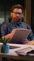 Caucasian business man trader businessman analyst writing document in night office paperwork overtime evening working online trading thinking write notes thoughtful guy male developer think ideas task video