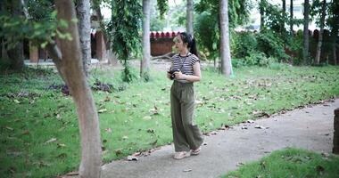 Handheld shot, Asian woman is enjoying a quiet walk while taking pictures of the surrounding nature, Enjoy holiday travel. video