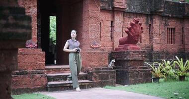 Handheld shot, Happy woman is enjoying a quiet stroll, taking photos of old sculptures and ancient brick structures, Enjoy holiday travel. video