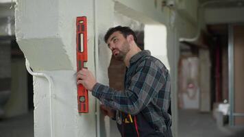 Engineer builder repair work on construction site man Caucasian guy architect measuring wall with bubble level tool building instrument male foreman electrician handyman repairman using measure ruler video