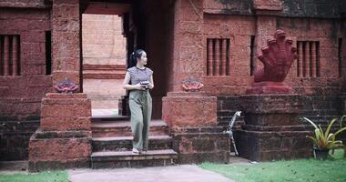 Handheld shot, Happy woman is enjoying a quiet stroll, taking photos of old sculptures and ancient brick structures. video