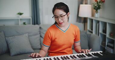 Handheld shot, A young Asian woman is happily playing a keyboard in a cozy living room. video