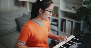 Handheld high angle view shot, A beautiful young woman is happily practicing her keyboard at home. Enjoy favorite musical instruments video
