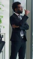 Vertical view pensive African American business man thinking in office looking out window create solution businessman male professional think idea decide work difficult thoughts pondering strategy video