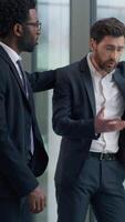 Vertical view two multiracial business men in office Caucasian sad frustrate businessman male near window African American guy partner supporting calming friendship businessmen discussing work problem video