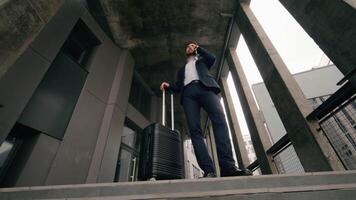 Caucasian middle aged business man arriving in new city talk cellphone standing near airport building with baggage suitcase talking mobile phone businessman order taxi employer travel trip concept video