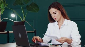 A focused young woman working on a laptop in a contemporary office environment, ideal for business, productivity, and modern workspaces concepts. video