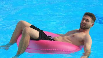 Handsome young man enjoying a swim in the pool on a hot summer day. Concept relaxation, confidence, summer mood. video