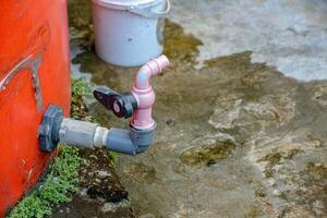 Water Tank with Faucet and Bucket on Wet Concrete Surface photo