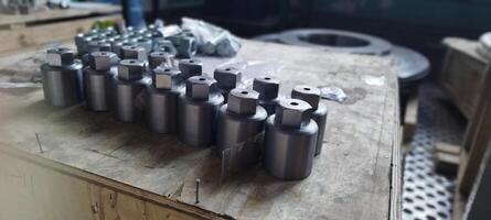 Cap nuts. Close-up manufactured metal parts with a hexagonal head. Industrial fasteners on a wooden surface. Metal components with a hexagonal head. Industrial parts arranged on a wooden surface. photo