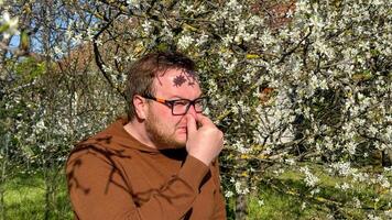 A contemplative Caucasian man in an orchard battles spring allergies, embodying the dance of Hanami and pollen whispers photo