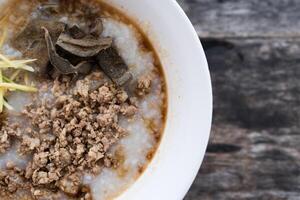 Congee, pork filling, boiled pork liver, and minced pork in a bowl. Easy breakfast. photo