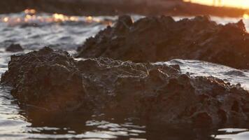 Rocky shallow beach at sunset, tracking shot slow motion video