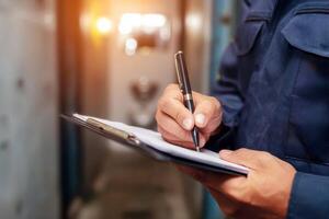 inspector takes notes on a clipboard while inspecting a warehouse . photo