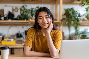 Portrait of young asia woman using laptop at cafe, she is working on laptop computer at a coffee shop. photo