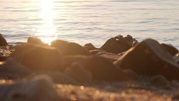 Rocky beach against calm sea sunset, static shot slow motion video