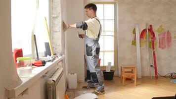 Construction worker removing old wallpaper during an apartment renovation, preparing walls for a fresh layer in a home improvement project focused on enhancing interior spaces video