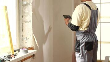 A man in overalls is standing in front of a window video
