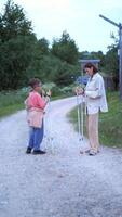 vertical Mother teaching her two children how to use nordic walking poles on a gravel path, promoting healthy lifestyle and family bonding in nature video