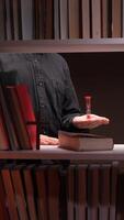 vertical Priest holding hourglass symbolizing passing time in library with books and cross video