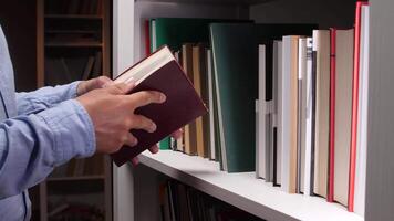 Close up of male hands holding dollar bills and hiding them behind books in a white library bookshelf, suggesting secret savings, illegal activities, or hidden funds video