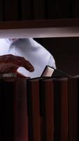 vertical close-up of a man putting a book on a bookshelf. A man returns a book to the library video