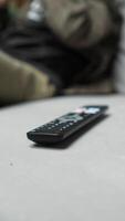 vertical Remote control resting on a cozy sofa in a living room, inviting a relaxing evening filled with entertainment and comfort while watching television. Soft cushions video