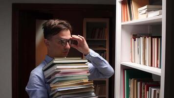 A man in glasses holding a stack of books video