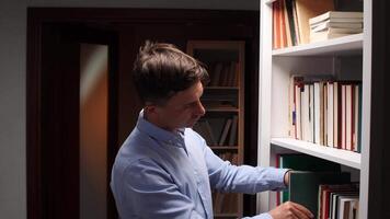 Researcher engrossed in a book, standing beside a white bookshelf in a library, deeply focused on the pages, embodying the pursuit of knowledge and learning in a peaceful environment video