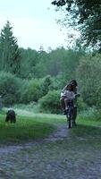 vertical Mother and daughter riding bicycles along a scenic rural road, surrounded by lush trees and a rustic wooden fence, cherishing joyful moments together in serene nature video