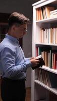 A man in a shirt and glasses is looking at a book video