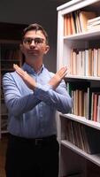 vertical Young librarian showing stop gesture with crossed arms, denying access to bookshelf in library or bookstore, protecting books and knowledge video