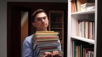 portrait Male librarian carrying a large stack of books in a library, surrounded by bookshelves filled with literature, showcasing the abundance of knowledge and information available video