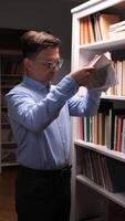 vertical man shakes hidden money out of book. Savings in book in library. Man with glasses shakes book, hidden dollar bills fly out of book video