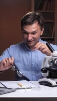 A man is looking at a microscope with a laptop video