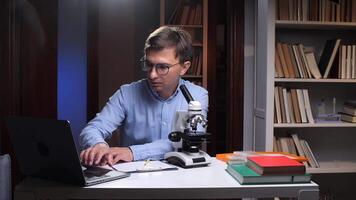 A man in glasses is working on a laptop computer video