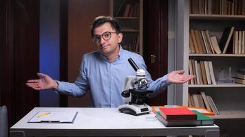 A man with glasses and a microscope in front of a desk video