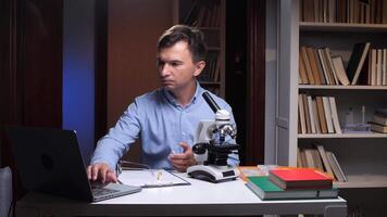 A man sitting at a desk with a laptop and microscope video