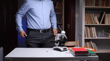 A man in a blue shirt is standing in front of a microscope video