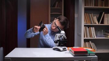 A man is looking through a microscope at a computer video