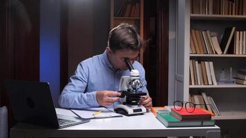 A man looking through a microscope at a laptop video