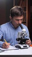 A man is looking at a microscope while sitting at a desk video