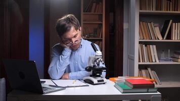 A man sitting at a desk with a laptop and a microscope video