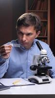 A man is looking at a microscope while holding a card video
