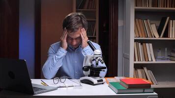 A man sitting at a desk with a microscope video