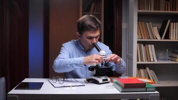 A man is looking through a microscope at a book video
