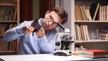 A man in glasses looking through a microscope video
