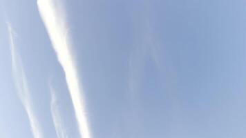 White line after flying airplane in blue sky at summer sunny day. Beautiful cloudscape at background. Close up Slow motion video